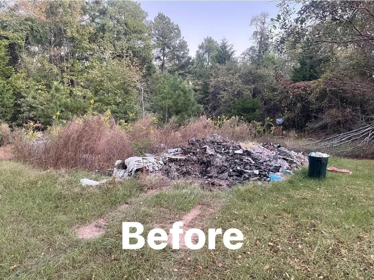 Before: Overgrown yard with large pile of debris and trash surrounded by wild vegetation and trees